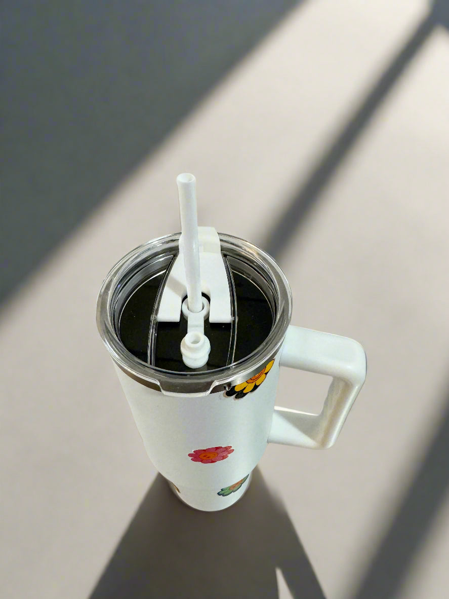 White tumbler with colorful designs on a metallic surface and tiled wall background